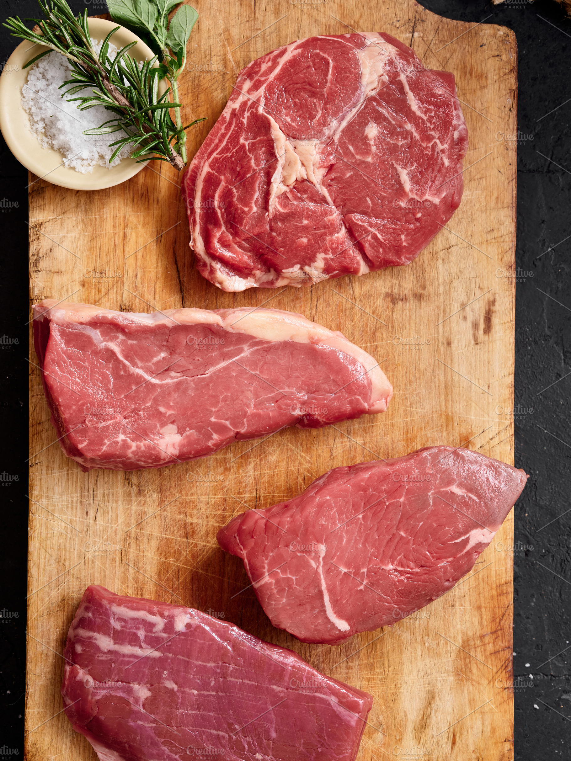 Raw beef cuts including rib-eye, roast beef, flank, and rump steak on wooden ch, a Food & Drink Photo by Asya Nurullina