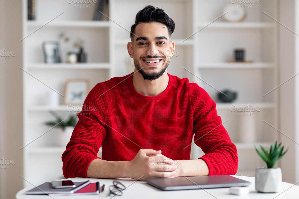 Portrait Of Smiling Handsome Arab Man Sitting At Desk In Home Office, a Photo by Prostock-Studio (Photo 1 of 2)