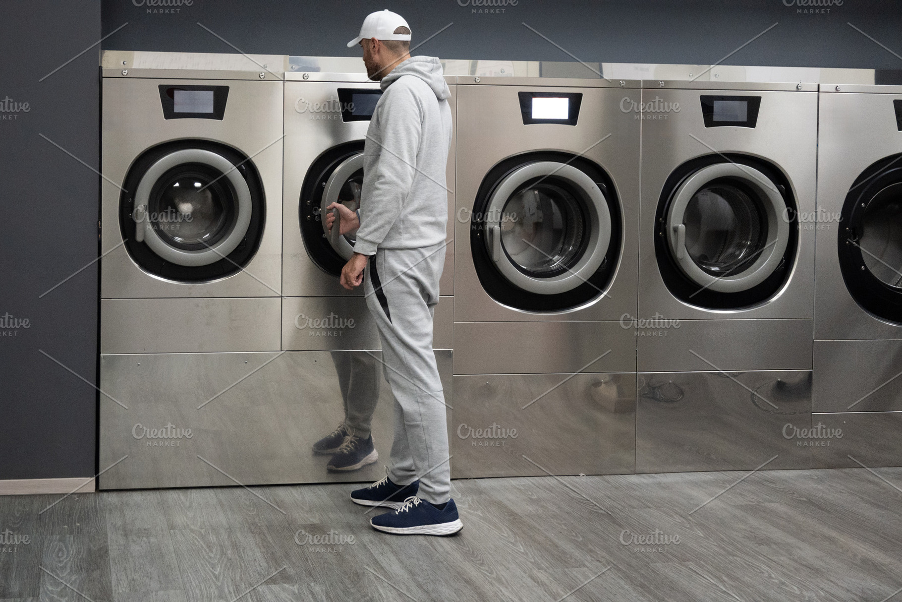 Man Using Self-Service Washing Machine in Modern Laundromat, a Person Photo by etorres69