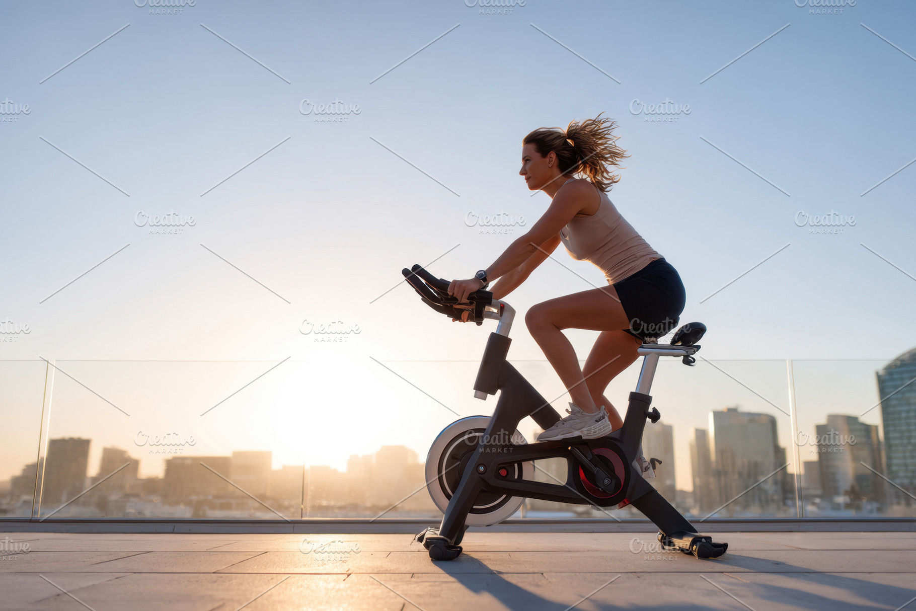 Woman cycling at sunset with city skyline, a Sports & Recreation Photo by AlyaAnd