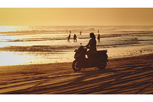 Woman riding scooter on sandy beach, a Person Photo by Goinyk