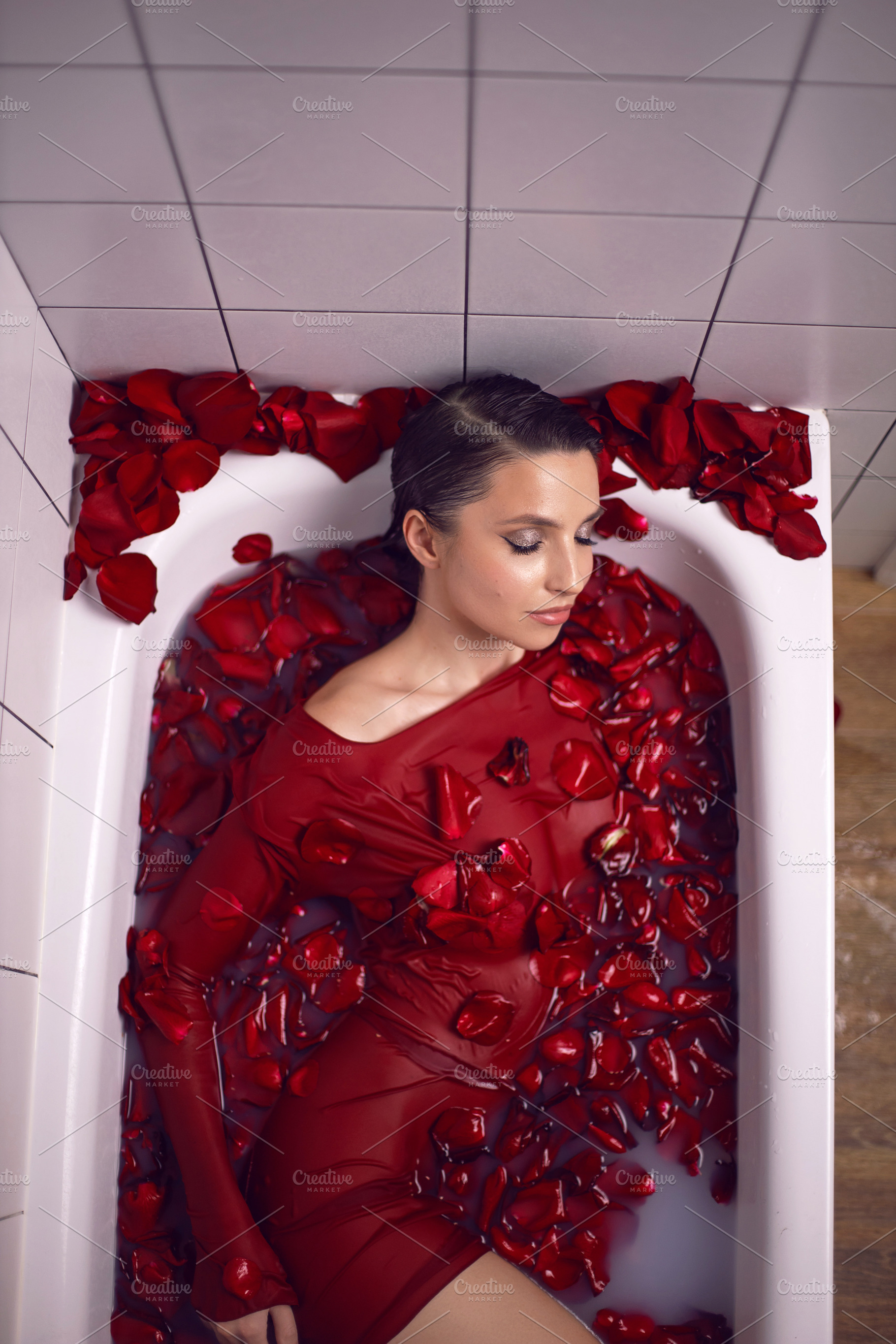portrait of a beautiful sexy woman in a red dress lies in a white bathroom with, a Person Photo by SaulichPhoto