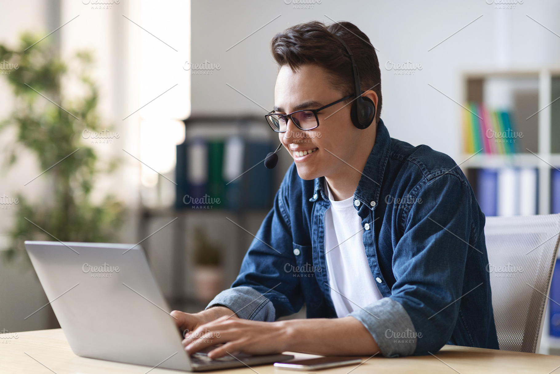 Telecommuting Concept. Young Male Manager In Headset Working With Laptop In Off, a Photo by Prostock-Studio