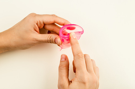 Female hands folding a menstrual cup, a Health & Medical Photo by Andriana Syvanych