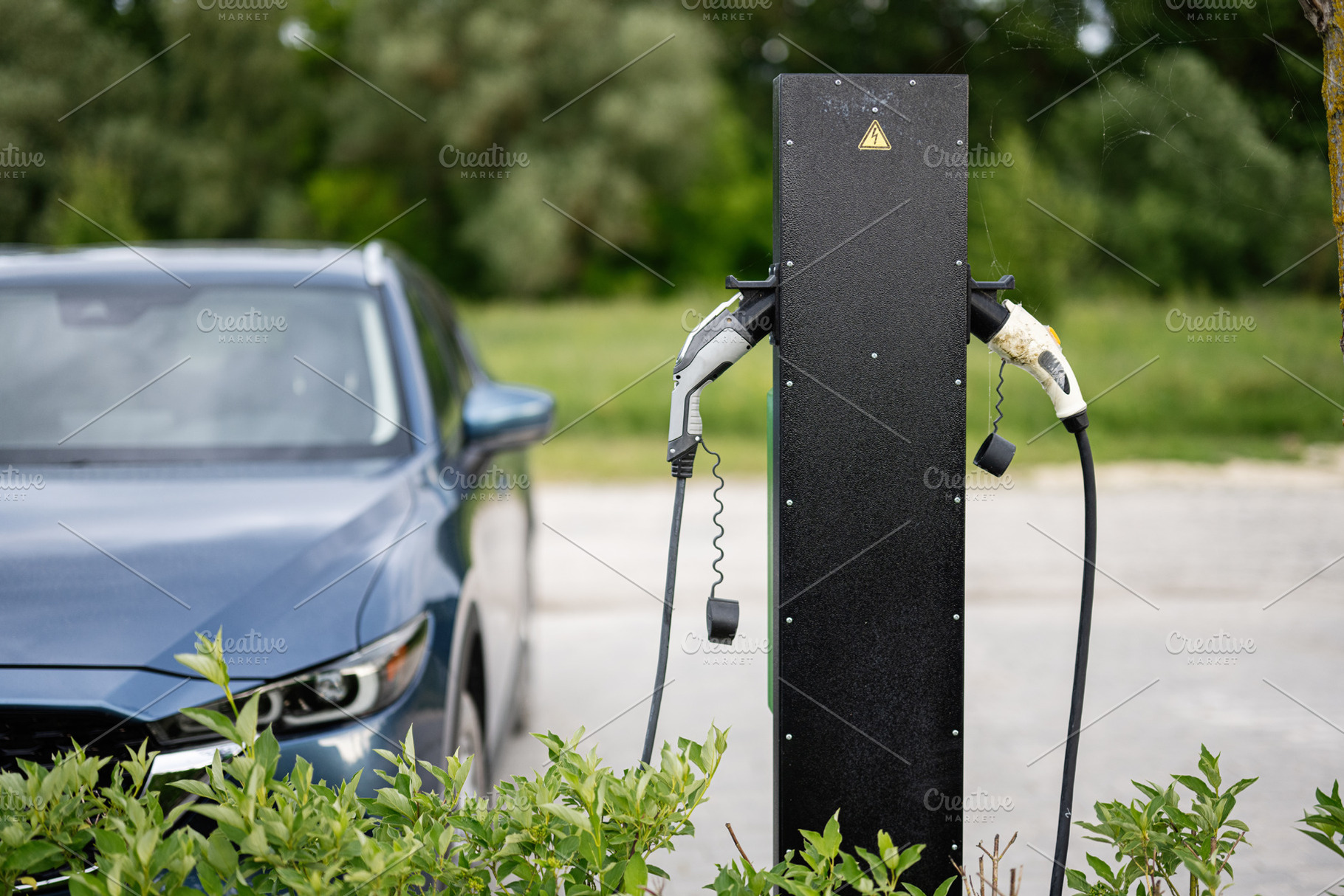 Electric vehicle charging station with greenery and parked car in background, a Photo by AS photostudio