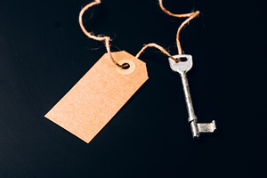 Key with blank kraft tag on dark, a Business Photo by Anna Efetova