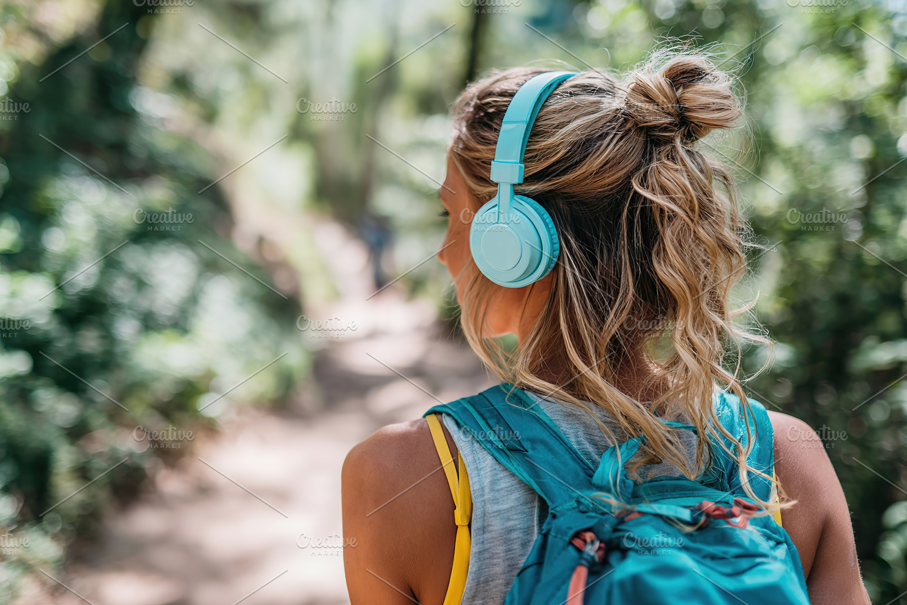 Enjoying nature sounds through headphones while hiking in a wooded area, a Person Photo by AlyaAnd