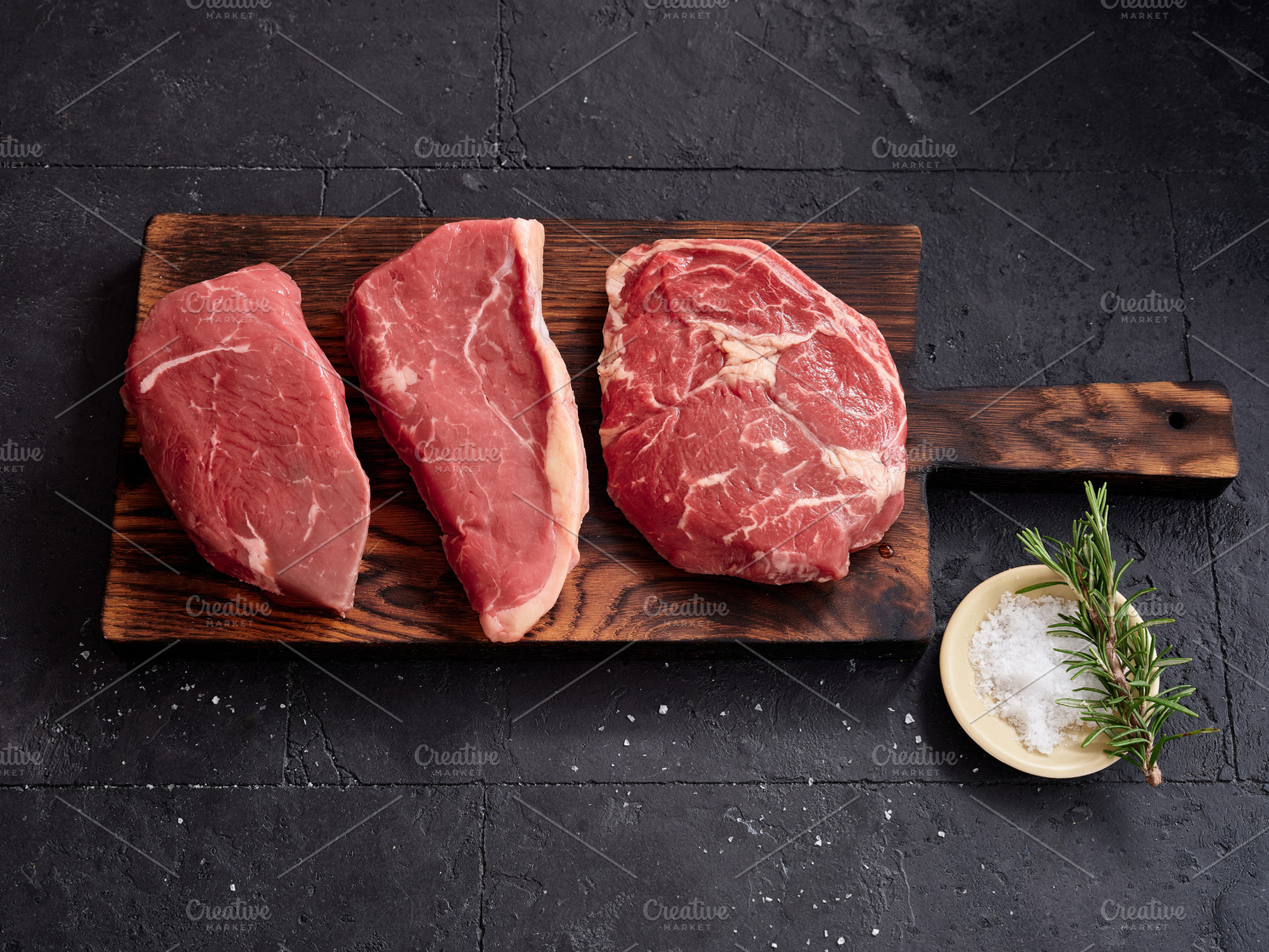 Raw rib-eye, roast beef, flank and rump steak on a wooden board with salt and h, a Food & Drink Photo by Asya Nurullina