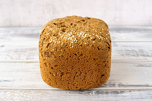Whole grain bread loaf with sesame seeds and flax seeds on a rustic wooden tabl, a Food & Drink Photo by Eugene_Photo