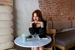 Stylish woman relaxing at cafe table with notebook and phone, a Person Photo by Photostock