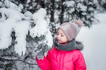 Little girl in a bright jacket plays in the winter forest, a Person Photo by Olena Rudo