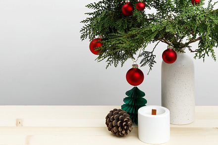 Vase with thuja branches, Christmas ornaments, pinecone, and candle for festive, a Photo by matucha