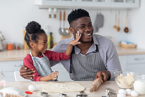 Joyful african american family having fun while baking, a Photo by Prostock-Studio