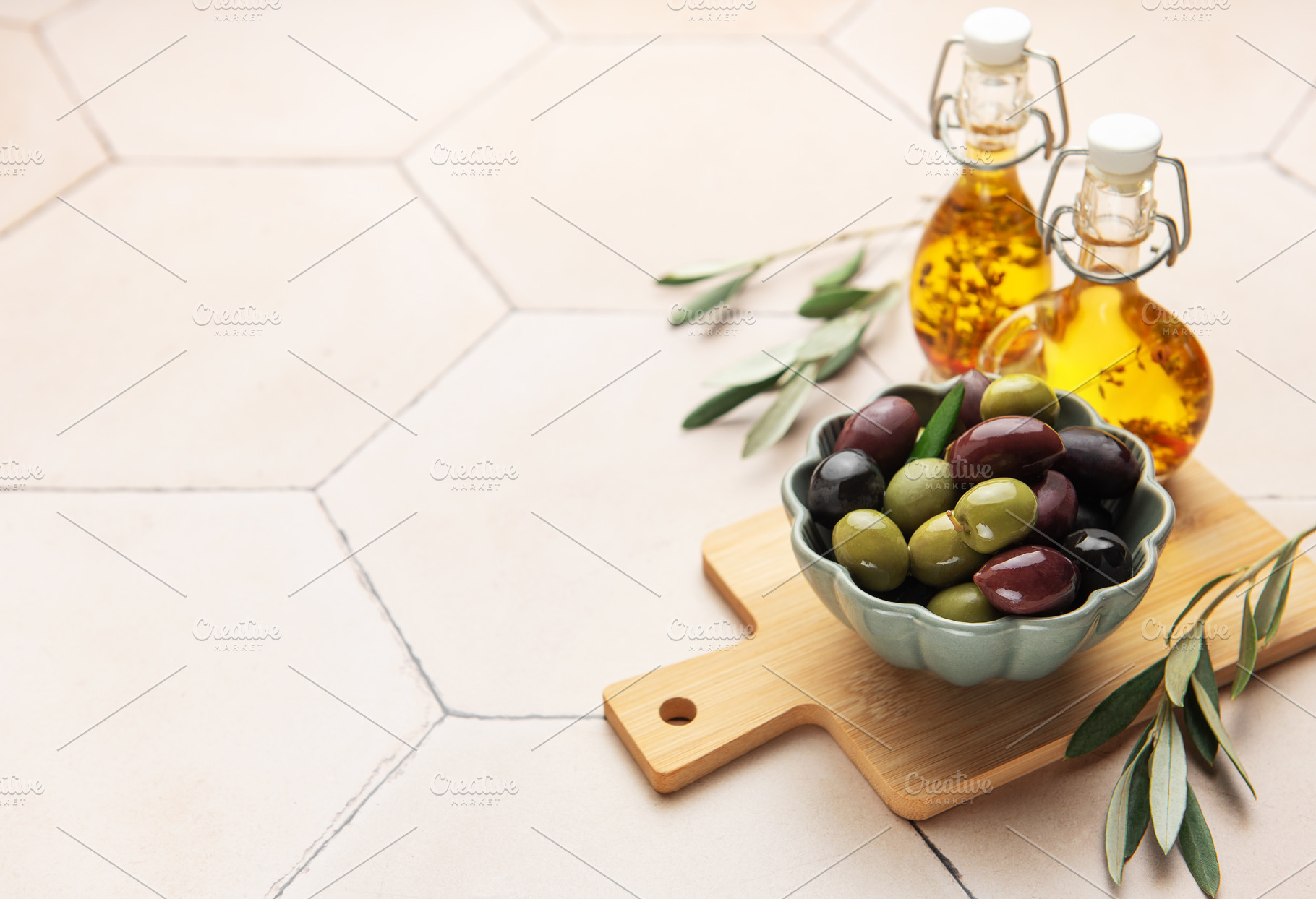 Green and black olives with olive oil on tiled kitchen counter, a Food & Drink Photo by Olena Rudo