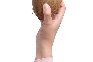 A woman's hand in pink clothes holds a whole brown coconut, a Food & Drink Photo by ndanko