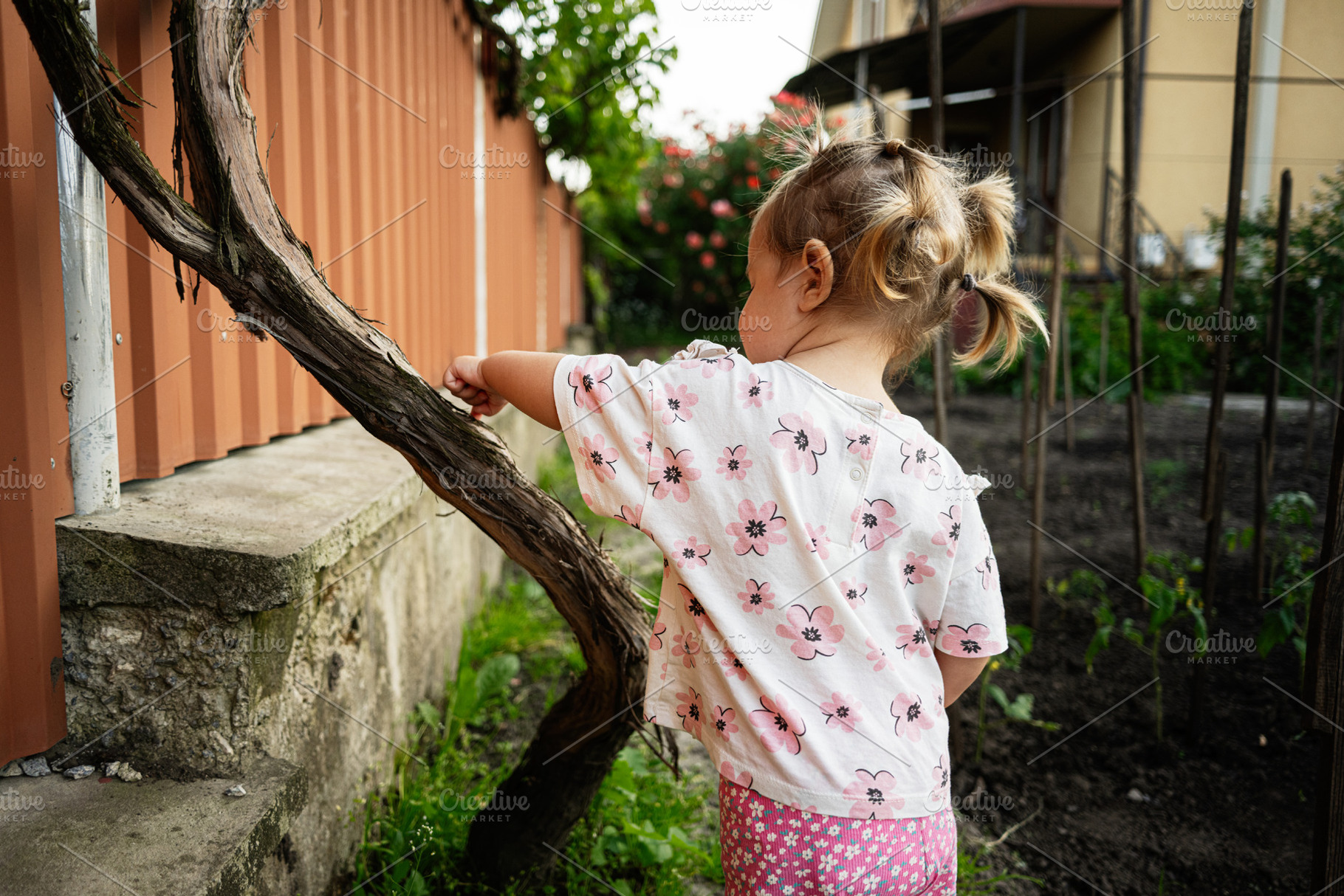 Little girl exploring backyard garden showing curiosity and innocence, a Person Photo by AS photostudio