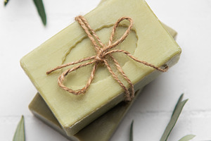 Natural olive soap bars tied with twine on white tile background, a Health & Medical Photo by Olena Rudo