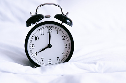 Black alarm clock on white bed. Time and hours concept. Interior, a Technology Photo by Ministocker