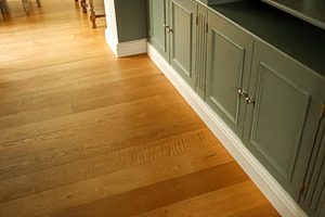 Hardwood flooring contrasting with sage green built in cabinetry and white base, a Photo by Studio ANNA