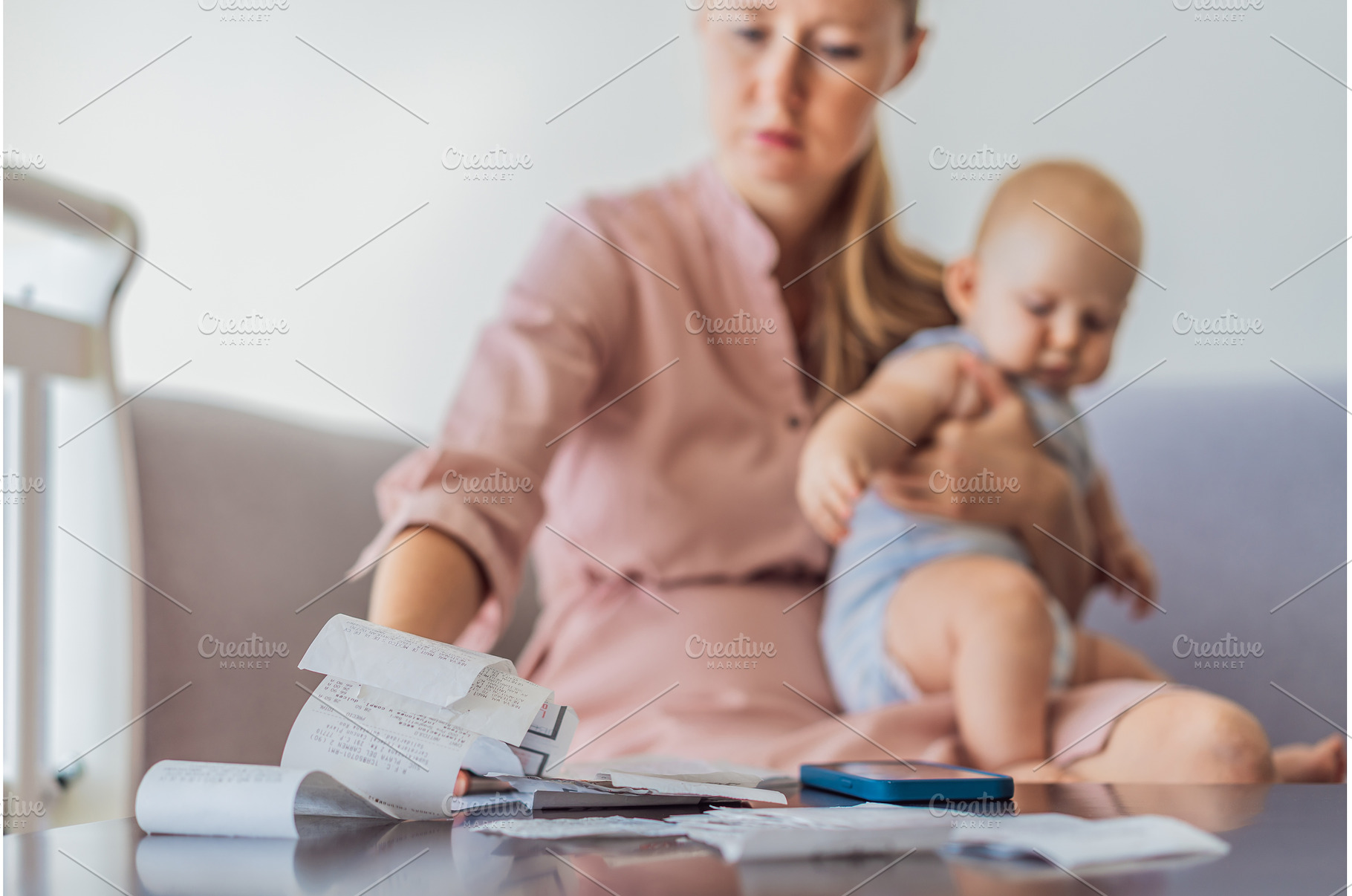 Mother sitting on sofa holding baby, a Business Photo by Elizaveta Galitskaya