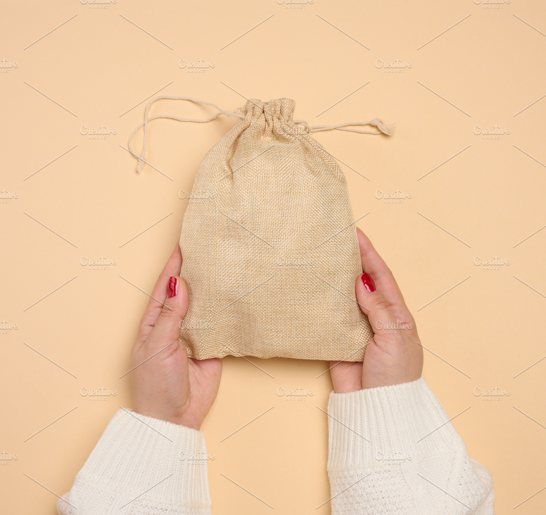 A woman's hands, clad in a white knitted sweater, hold a burlap, a Person Photo by ndanko