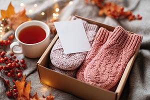 Cozy autumn-themed care package with warm socks and tea in a rustic setting, a Photo by AlyaAnd