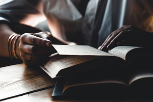 A woman is reading a book education featuring background, woman, and hand