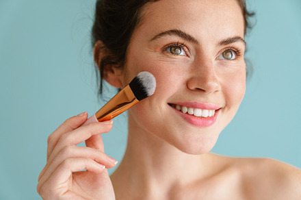 Half-naked brunette woman smiling while using cosmetic brush, a Person Photo by Dean Drobot