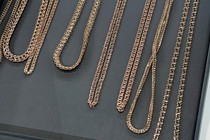 Elegant collection of gold chain necklaces displayed on a luxury black tray, a Photo by AS photostudio