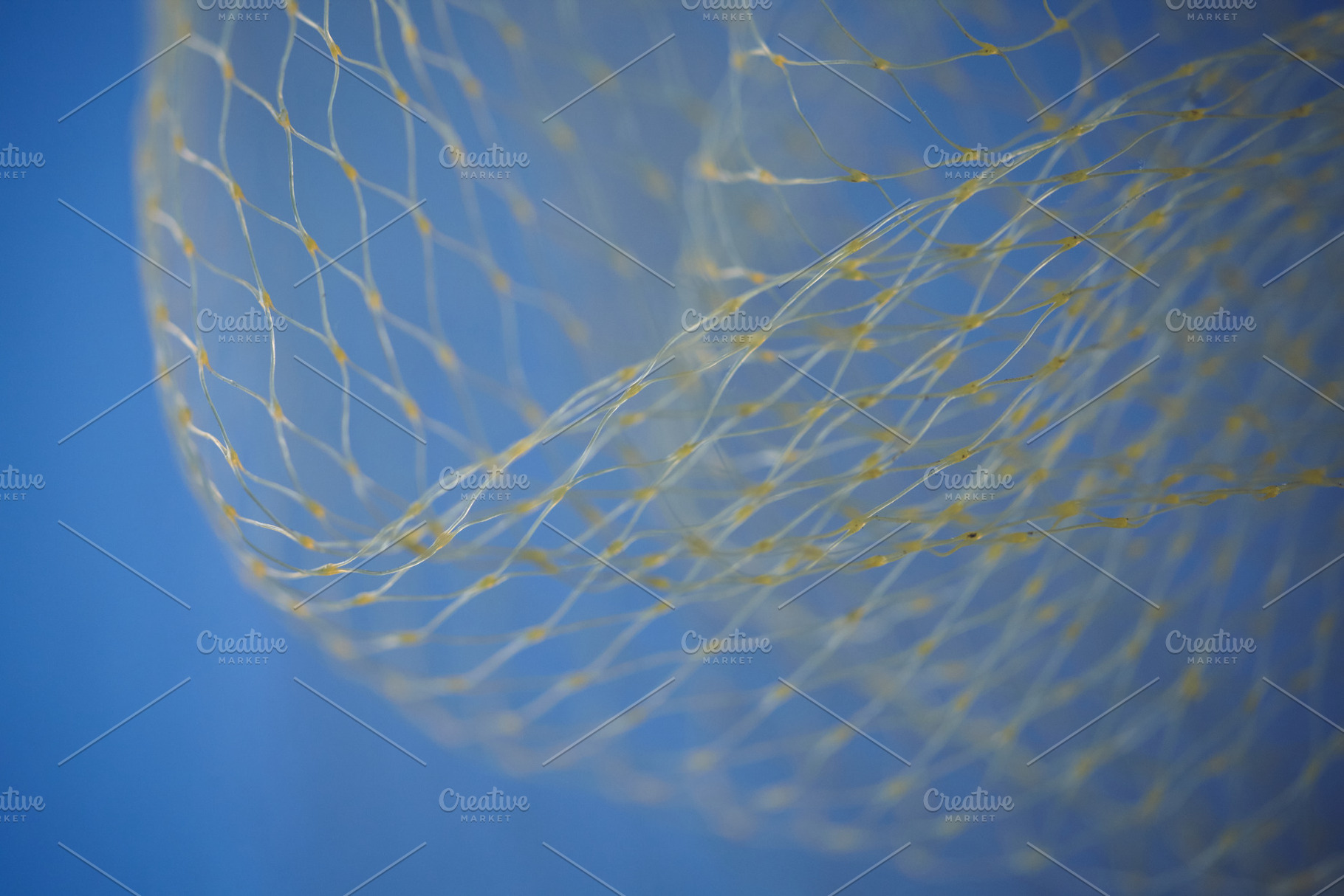 Abstract wave of yellow nylon mesh against a bright blue sky. Close-up of decor, an Abstract Photo by Rohan Photography