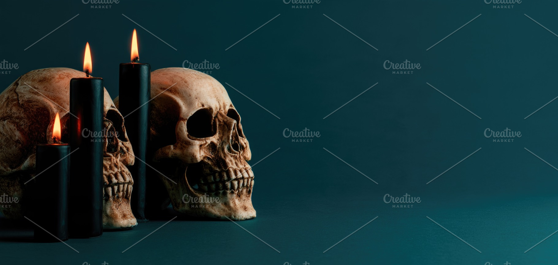 Halloween skull with black candles on dark teal background, a Person Photo by José Manuel Gelpi