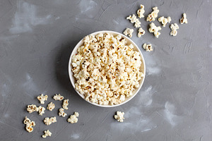 Popcorn in white bowl on grey table. Top view with copyspace