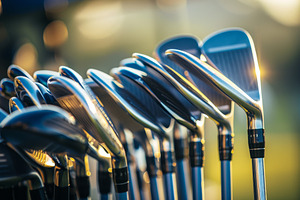 A collection of golf clubs is lined, a Photo by Tanuart