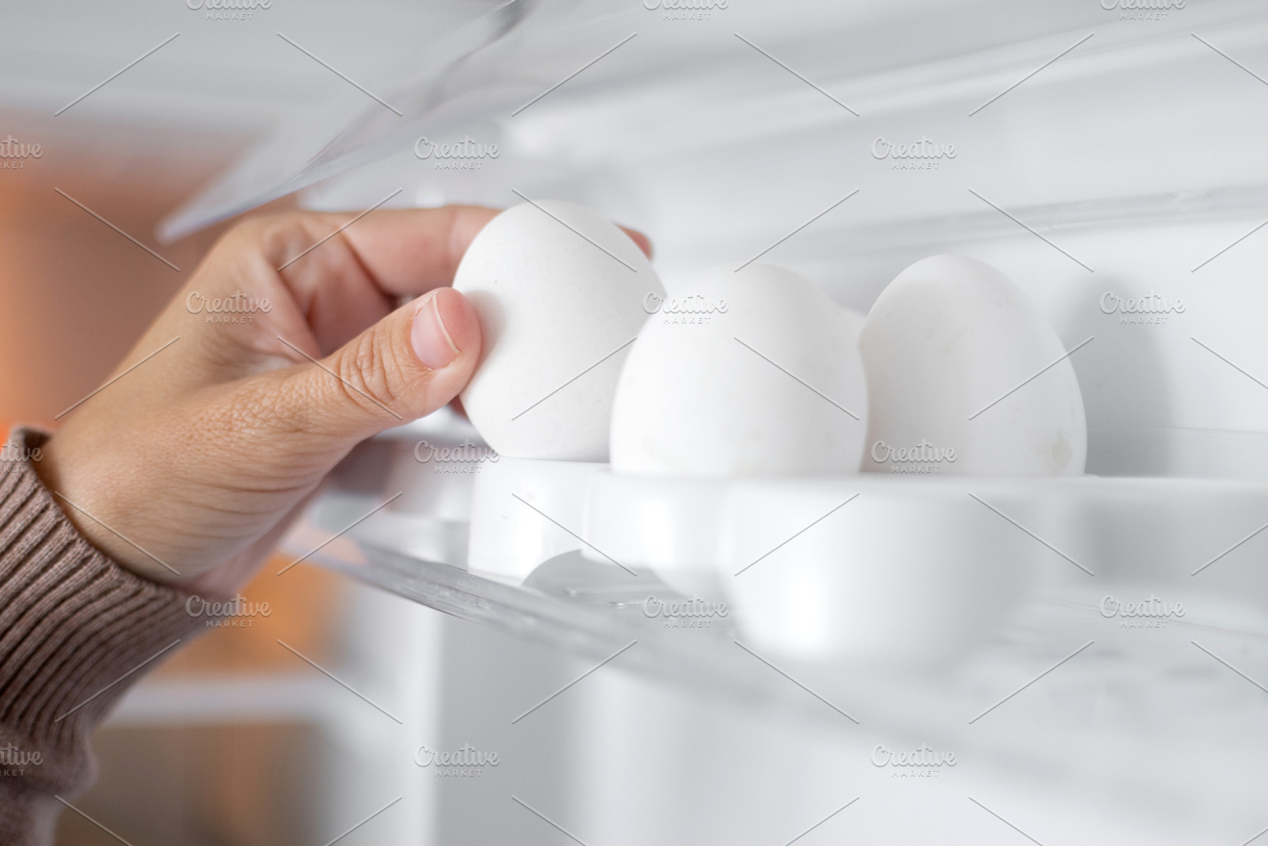 Hand taking fresh eggs from refrigerator door tray at home, a Food & Drink Photo by etorres69