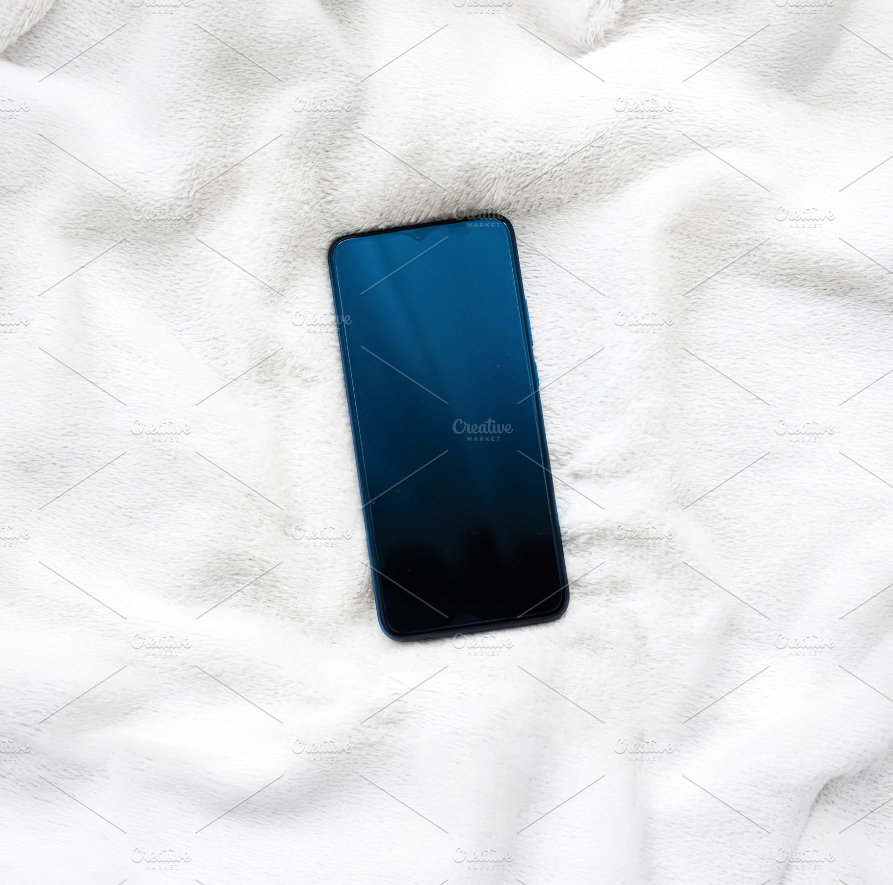 Smartphone resting on white fluffy blanket, representing modern communication,, a Photo by Studio ANNA