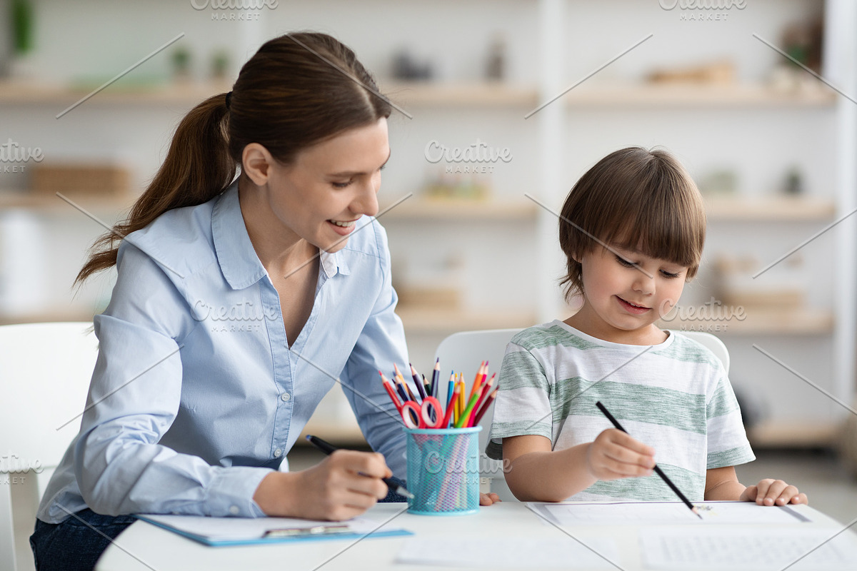 Early development training. Concentrated little boy pupil painting with teacher, a Photo by Prostock-Studio (Photo 2 of 2)