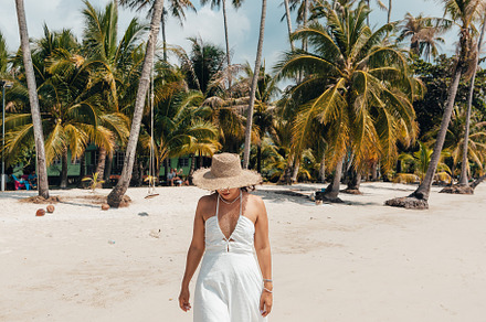 A woman in a hat enjoys the summer sun on a beautiful tropical b, a Holiday Photo by Art Rachen