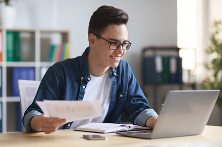 Office Work. Portrait Of Smiling Young Entrepreneur Working With Papers And Lap