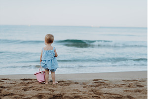 Toddler standing on sand beach with, a Person Photo by HalfPoint