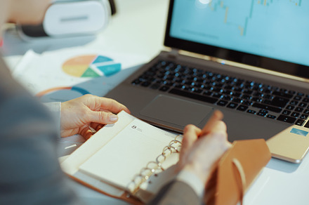 Closeup on modern woman with laptop writes in notebook, a Business Photo by Alliance Images