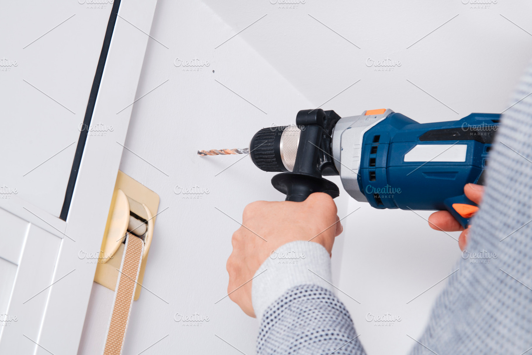 a man drills a hole in a wall with a drill, a Photo by Nito