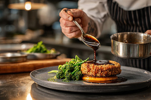 Chef plating gourmet dish dark sauce, a Photo by Pixeness Studio