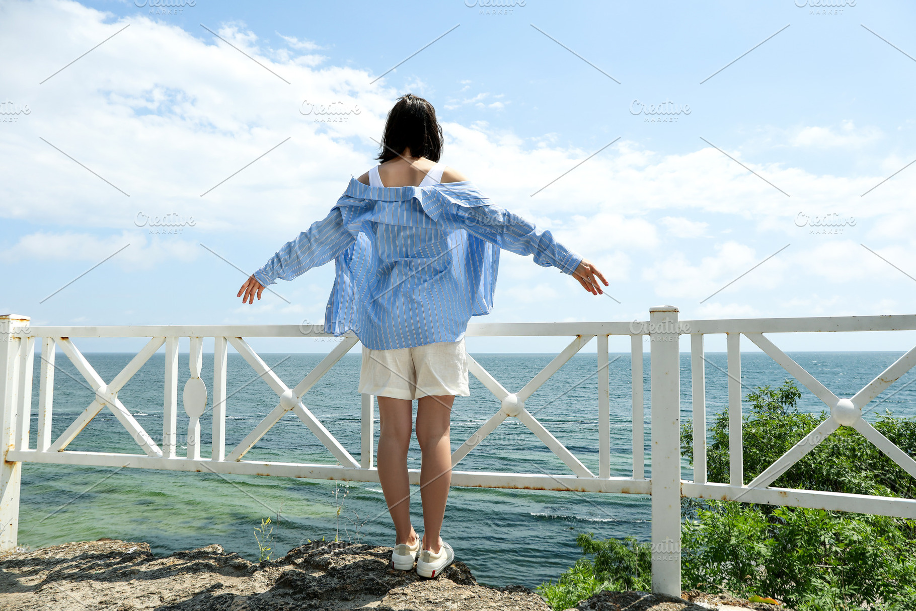 Young woman standing near sea in sunny summer day, a Holiday Photo by AtlasStudio PRO
