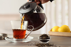 People serving a cup of tea on wooden kitchen bench, a Food & Drink Photo by Davizro's Market