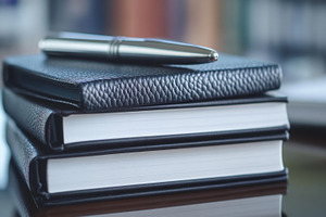 Elegant Silver Pen on Leather Notebooks Stack Close-Up, an Abstract Photo by Natalia Klenova's Shop