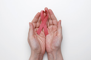 Pink awareness ribbon held gently in female hands for breast cancer advocacy, a Photo by matucha