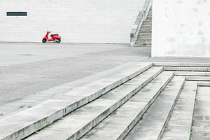 Red scooter against white wall, a Transportation Photo by BOOCYS