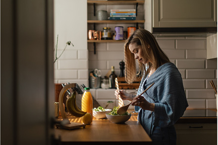 Young woman preparing salad in her, a Food & Drink Photo by HalfPoint