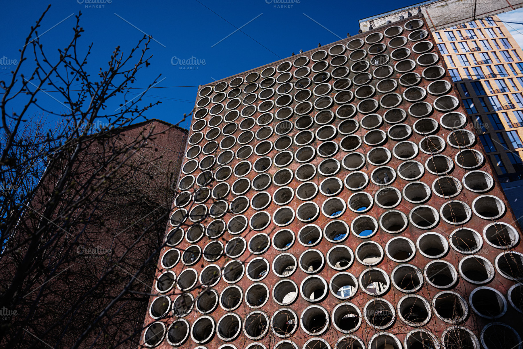 Round porthole facade of a modern urban building under daytime sky, a Photo by AS photostudio