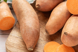 Whole and sliced sweet potatoes on wooden board, a Food & Drink Photo by Olena Rudo
